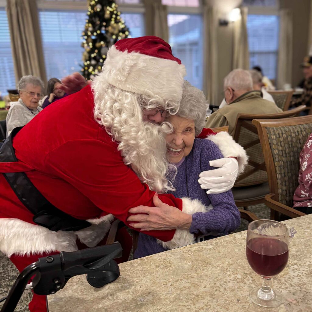 Santa Claus shares a hug with a senior woman at Cedar Trails Senior Living.